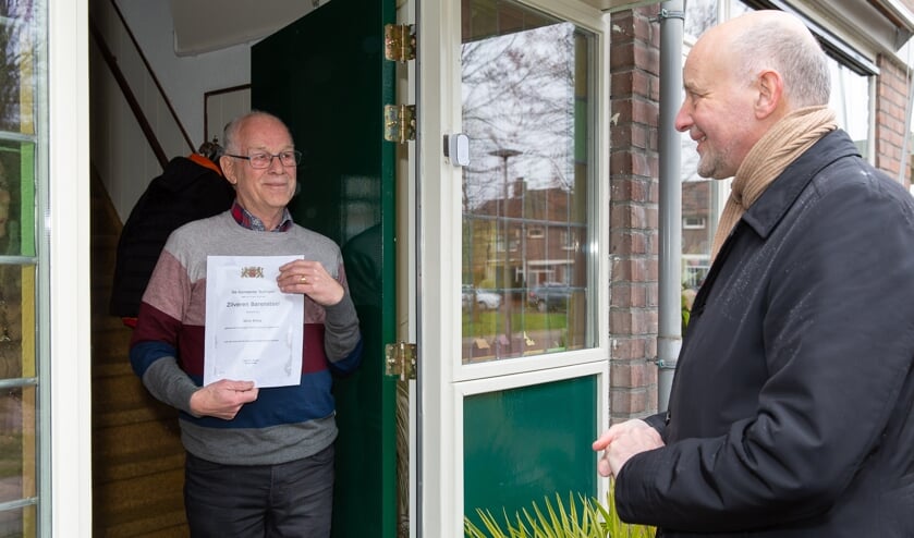 <p>Wim Prins ontvangt aan de deur de Zilveren Barensteel van wethouder Arno van Kempen. </p>