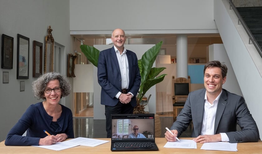 <p>Wethouders Marlies Volten en Arno van Kempen (staand) ondertekenen de overeenkomst met ontwikkelmanager Stefan van Vliet (rechts). Ontwikkelaar Ewoud Swaak is digitaal aanwezig. | Foto: pr.</p>